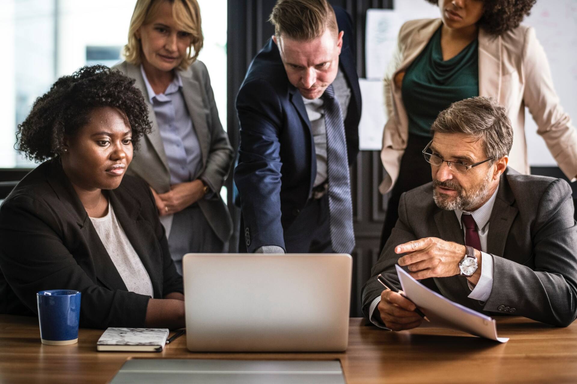 Image of five people talking and looking at a laptop