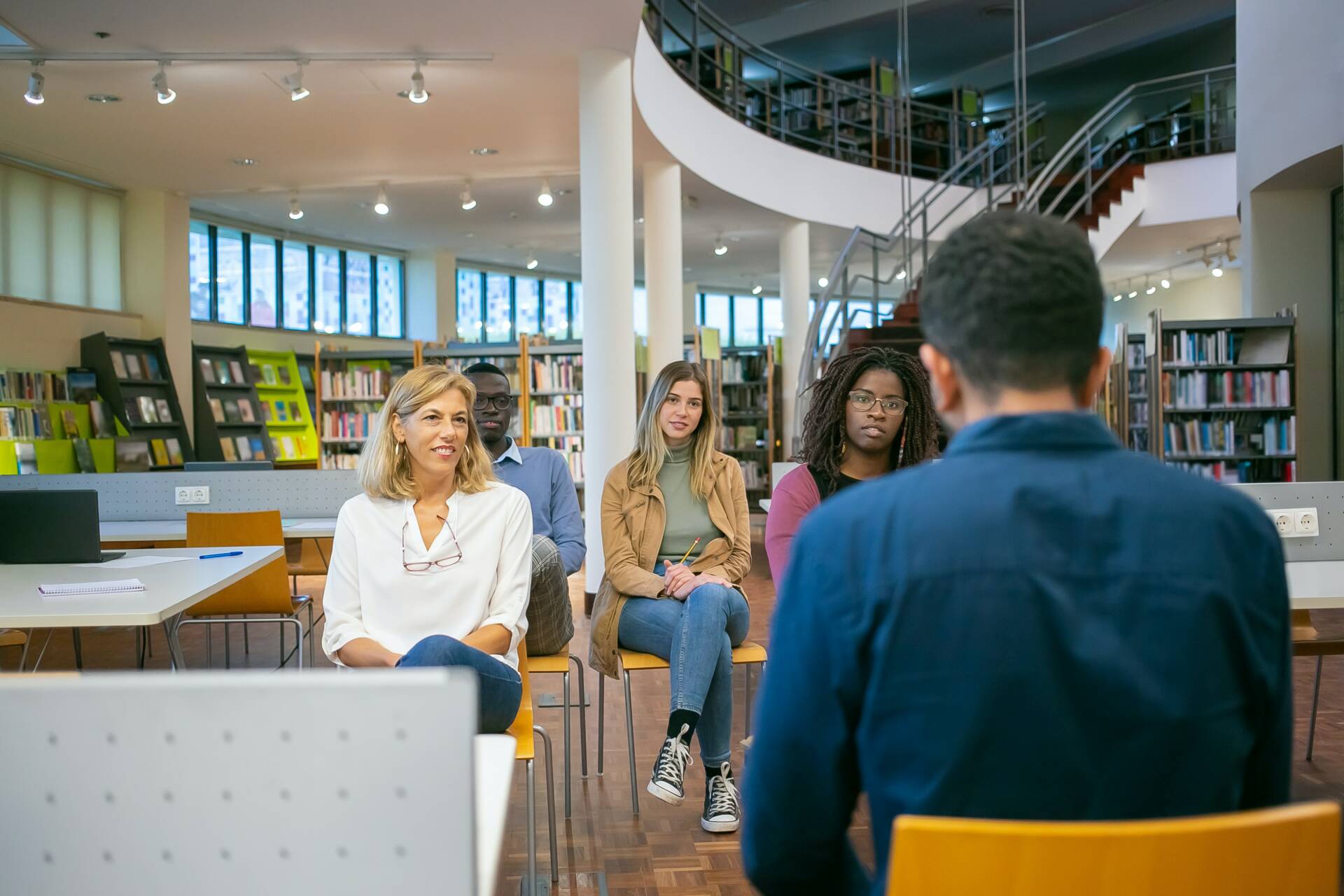 People sitting in a library listening to a person speak.